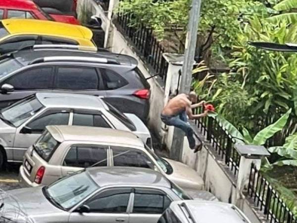 Suspek memanjat pagar selepas berjaya melepasi kawat duri yang dipasang di kawasan PKPD PPR Pantai Ria, Kuala Lumpur. - Foto tular Facebook