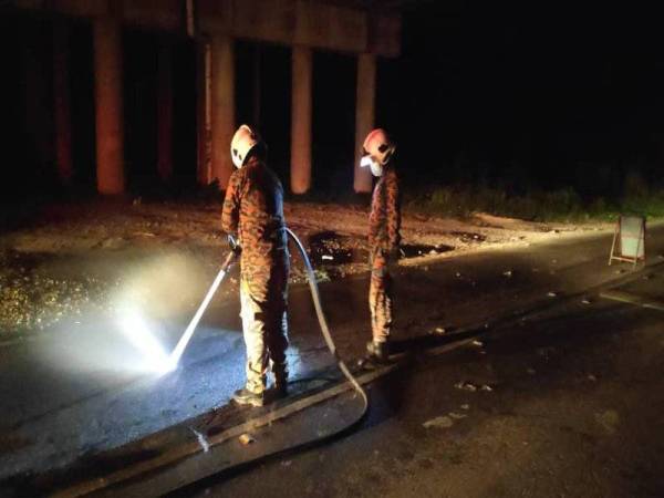 Anggota bomba melakukan pembersihan minyak di bawah jejambat LATAR, Parit Mahang di sini pada Ahad.