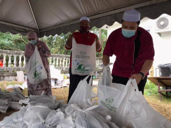 Muhammad Abdul Munib (kanan) melihat pek makanan yang disediakan untuk agihan kepada 180 penduduk di Kampung Pulau Tukang Dollah yang dikenakan PKPD.