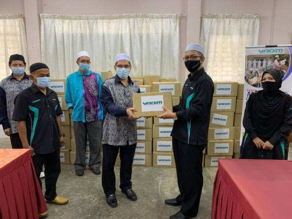 Ahmad Fathan (kanan) menyampaikan 200 Kit Musa’adah kepada Ahmad Pakhruddin di sini.