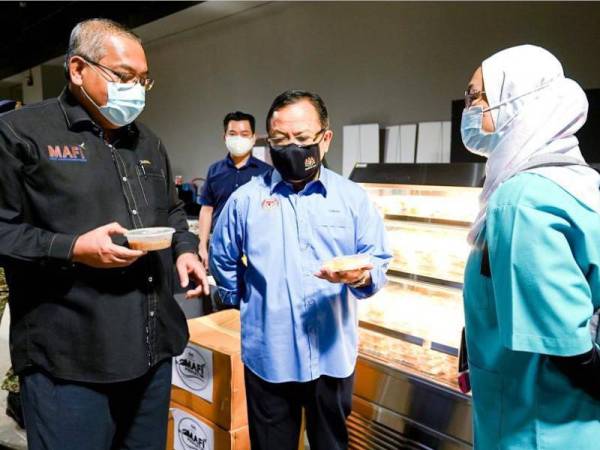 Ahmad Hamzah (tengah) sedang berbincang sesuatu dengan wakil MAFI ketika menyampaikan bantuan MAFI Prihatin kepada petugas barisan hadapan di PPV MITEC pada Isnin.