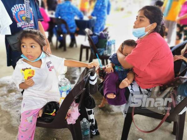 Norshila memeluk erat anak lelakinya yang lemas bersama seorang lagi anak perempuannya (kanan) selepas perahu yang mereka naiki terbalik sebelum diselamatkan penduduk kampung dalam kejadian kebakaran di Kampung Tanjung Aru Baru, Kota Kinabalu.