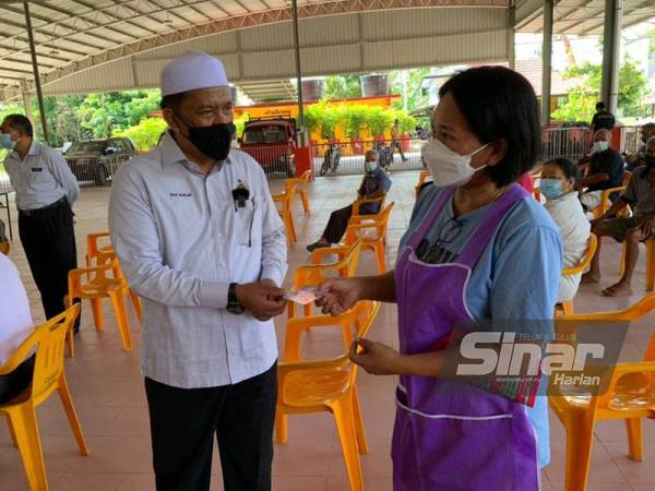 Wan Roslan (kiri) berbual dengan seorang penduduk yang hadir mendaftar unuk mendapat vaksinasi di Wat Machimmaran, Jubakar Barat, Tumpat.