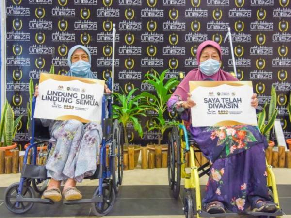 Zalilah (kiri) dan Aminah teruja menerima suntikan vaksin bersama-sama di PPV UniSZA di Kuala Nerus pada Selasa.