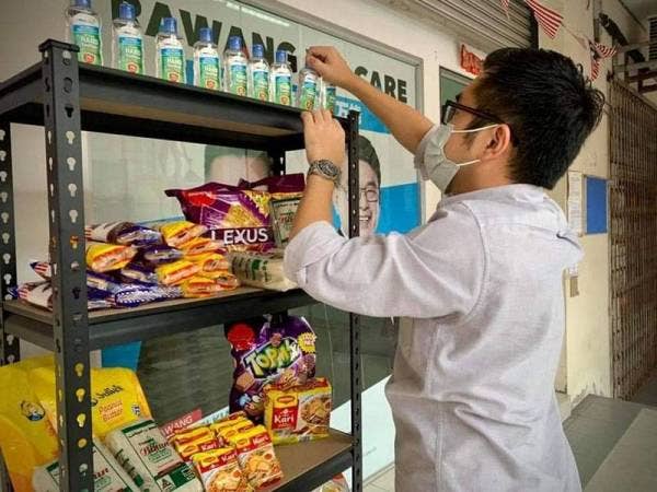 Wei Kiat menyusun bahan asas yang diletakkan di Food Bank di luar pejabatnya bagi memudahkan penduduk terputus bekalan mendapatkan makanan.