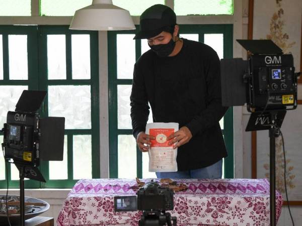 Mohd Fais Hafiz menyusun produk milik peniaga dan usahawan kecil sebelum merakamkan foto dan video ketika ditemui di Kampung Pulau Duyong. - Foto Bernama