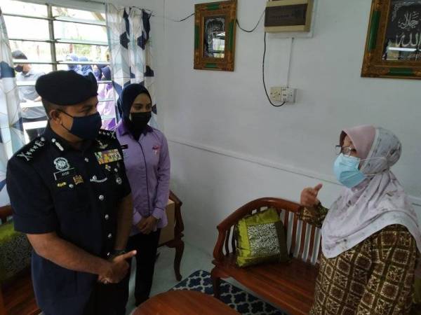 Ayob Khan (kiri) bertanya khabar Maimunah (kanan) yang menerima sumbangan Op Bantu di rumahnya di Jalan Kebun Teh di sini pada Rabu.