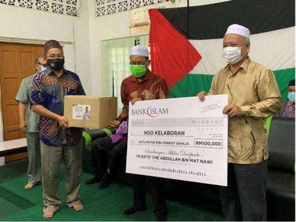 Che Abdullah (tengah) menyampaikan replika cek untuk Bantuan Bakul Makanan di bawah parlimennya.