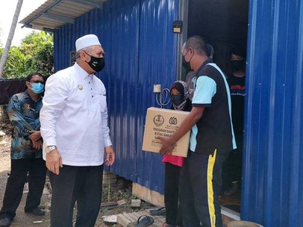 Razman menghulurkan bakul makanan ketika turun padang melawat Shahrunizam.