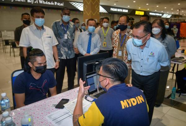 Menteri Utiliti Sarawak Datuk Seri Dr Stephen Rundi Utom (kanan) meninjau kaunter pendaftaran pusat pemberian vaksin industri (PPVIN) di Mydin Petra Jaya, hari ini. -Foto Bernama