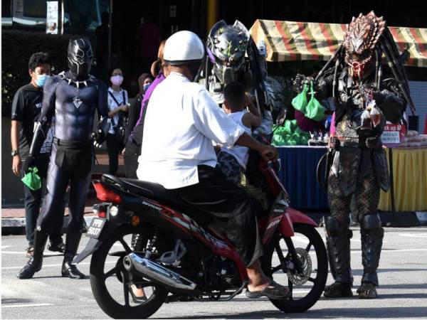 'Predetor' dan 'Black Panther' mengedarkan bungkusan sarapan percuma kepada orang awam yang melalui Jalan Larut, pada Khamis. - Foto Bernama

