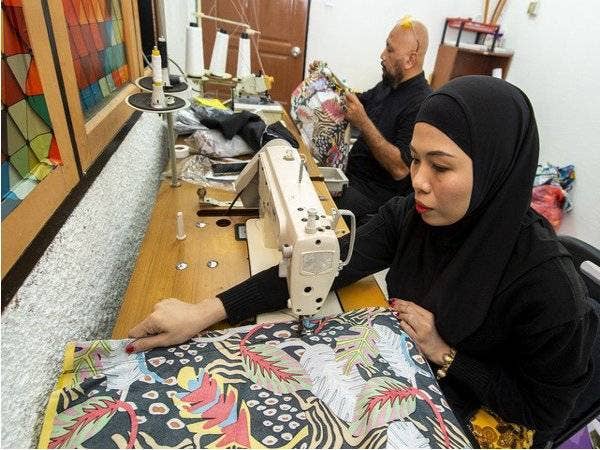 Zarina bersama suami Mohd Rosoliza menjahit seluar 'Separuh Rindu' yang ditempah oleh pelanggannya ketika ditemui Bernama di rumahnya di Kubang Kerian hari ini. - Foto Bernama