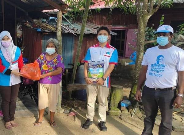 C. Subramani (kanan) bersama pasukan gerak kerjanya mengagihkan bantuan 'bakul makanan' kepada salah seorang penerima.