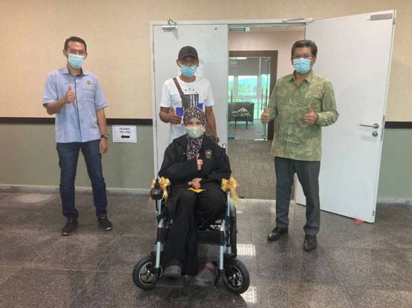 Normelisa (duduk) menerima kerusi roda elektrik sumbangan Pejabat Wakaf dan Infaq UniSZA bagi memudahkan pergerakannya ketika menjalani latihan industri.