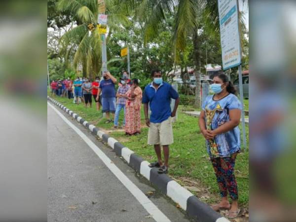 Orang ramai beratur dalam hujan untuk mengambil bantuan menerusi Program Runcit Truck N43 di Rumah Pangsa Permas Jaya, Pasir Gudang, pada Khamis.