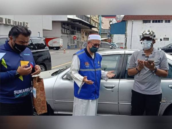 Dr Zulkifli (tengah) berdoa semoga urusan lelaki itu dipermudahkan sebelum menyerahkan sumbangan kepadanya pada Jumaat.