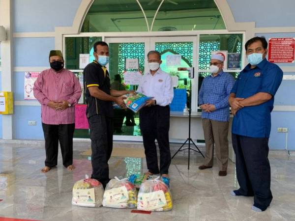 Mustapa (tengah) menyampaikan sumbangan kepada penduduk di Kampung Berdang pada Sabtu.