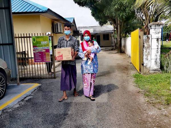 Furidah dan suaminya bersama bayi mereka berusia dua bulan mengambil kotak bantuan makanan