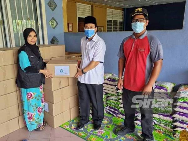 Dari kanan: Adlan dan Suhaimi menyerahkan set makanan asasi kepada salah satu Rakan Strategik Agihan Fidyah MAIS untuk diagihkan kepada golongan yang terkesan akibat pandemik Covid-19 di sekitar Kuala Langat.