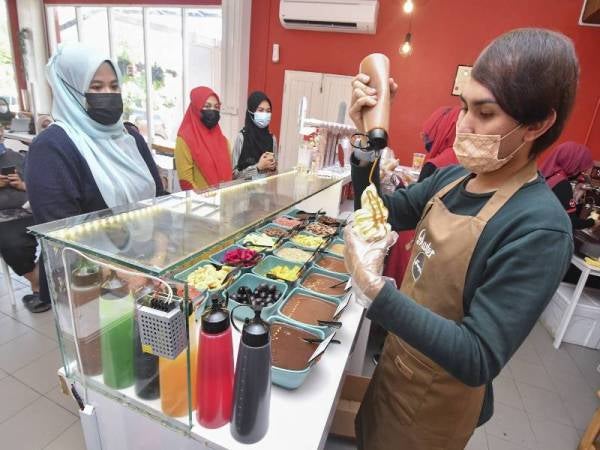 Mohamad Hafizuddin menyiapkan yogurt beku yang dipesan pelanggan. - Foto Bernama