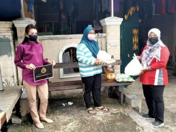 Yusnani Arshad (tengah) menerima sumbangan Permata bagi meringankan beban keluarganya di Jalan Nanas, Taman Kota Masai, Pasir Gudang pada Sabtu.