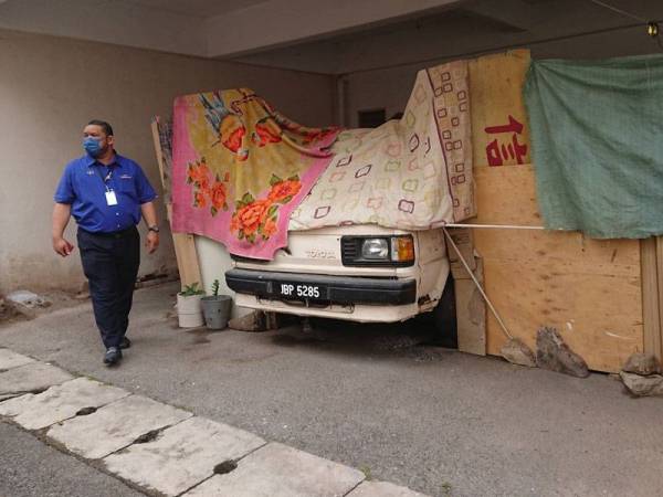 Muhammad Ayyad melihat belakang bangunan kedai yang menjadi tempat tinggal tiga individu itu di Taman Merdeka, Batu Berendam.