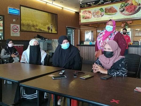 Noratikah (duduk, kanan) bersama sebahagian peniaga ketika sidang akhbar di sebuah premis di Pasar Raya Besar Mydin Meru Raya, di sini pada Rabu.