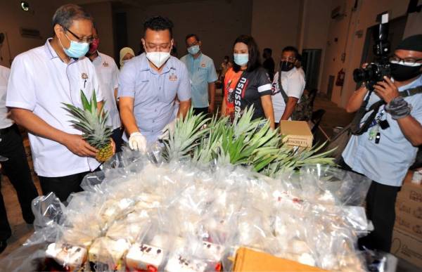 Mohd Hairi (dua dari kiri) menyediakan bahan yang akan diagihkan kepada orang ramai untuk Program Bank Makanan di Dewanraya Taman Perbadanan Islam, Kebun Teh, Johor Bahru, pada Rabu.