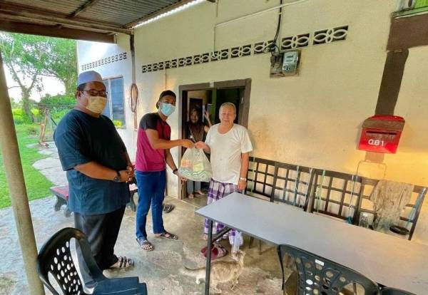 Mohd Syafiq (kiri) bersama rakannya menyerahkan barangan makanan sebagai inisiatif membantu keluarga terjejas akibat pandemik Covid-19.