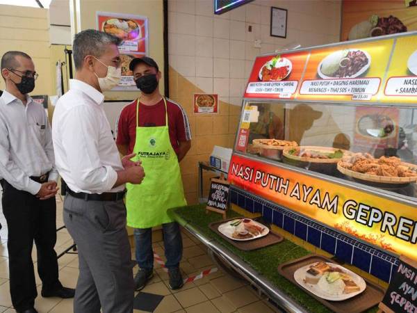 Tengku Zafrul (kanan) beramah mesra dengan seorang peniaga pada program Tinjauan Mesra ke Kiosk D'Harmoni@9 dan Medan selera Presint 9 pada Rabu. - Foto Bernama