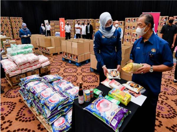 Muhyiddin diiringi Menteri Pembangunan Wanita, Keluarga dan Masyarakat Datuk Seri Rina Mohd Harun melihat barang-barang keperluan asas semasa meninjau penyediaan Bakul Prihatin Negara di Kementerian Pembangunan Wanita, Keluarga dan Masyarakat, pada Khamis. - Foto Bernama