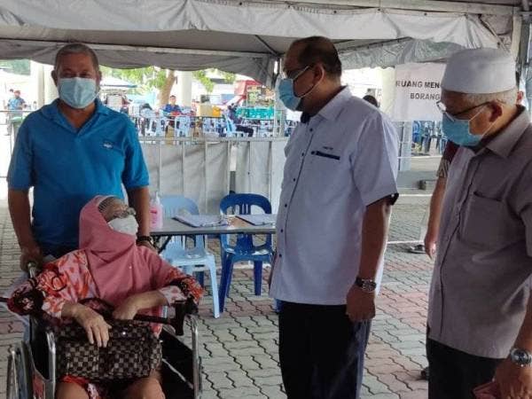 Ahmad Amzad (dua dari kanan) dan Dr Mohd Hayati (kanan) menyantuni seorang warga emas semasa melawat Pusat Pemberian Vaksin Kota Setar di Stadium Sultan Abdul Halim pada Khamis.