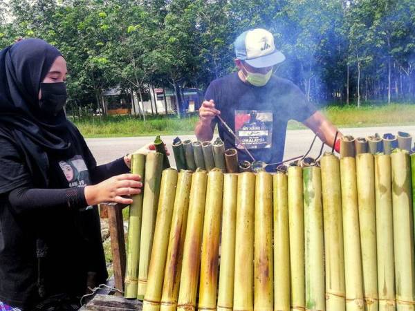 Hanafiah Mohd Noor, 38, bersama isterinya, Nor Adila Ramli, 30, membakar lemang tiga perisa menjelang Aidiladha dengan meletakkan nama 'Lemang Guling Bakar Original 100 Peratus'. Foto - Bernama