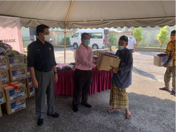 Zulkifle (kiri) menyaksikan Datuk Dr Zulkepli menyampaikan bantuan kepada mereka yang memerlukan.
