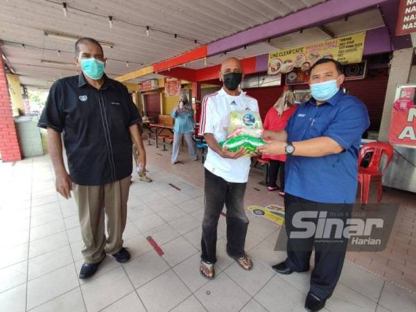 Penyelaras Dewan Undangan Negeri (DUN) Suka Menanti, Mohd Zaidi Mahamud (kanan) menyerahkan sumbangan bakul makanan kepada penerima sambil diperhatikan Pengerusi Persatuan Penjaja dan Peniaga Kecil Melayu Kedah Cawangan Kota Setar, Mohd Kholib Hamid (kiri) selepas Program Bantuan Penjaja untuk Penjaja di Medan Selera Mergong, di sini, pada Sabtu.