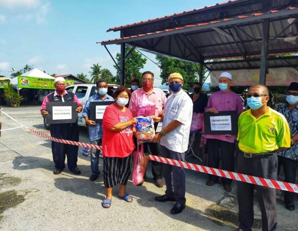 Mohd Asri Redha (tiga dari kanan) menyampaikan bakul makanan kepada salah seorang waris kanak-kanak yang dipilih untuk menerima bantuan di Simpang Empat di sini pada Sabtu.