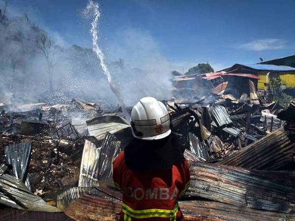 Anggota Jabatan Bomba dan Penyelamat Labuan bertungkus lumus memadamkan kebakaran dalam kejadian di Kampung Batu Arang pada Sabtu. - Foto Bernama