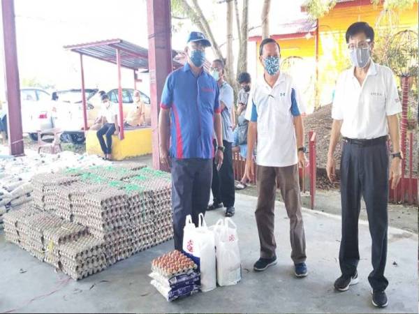 Noh (kiri) menyerahkan sumbangan bakul makanan kepada wakil penduduk kaum Cina di Tokong Pekan Tanjong Karang pada Sabtu.