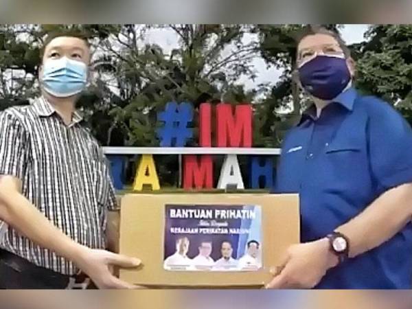 Saifuddin (kanan) menyerahkan bungkusan makanan kepada wakil Huazhong selepas Majlis Penyampaian Sumbangan Bersama Gabungan Pertubuhan Cina Malaysia (Huazhong) secara maya pada Ahad.