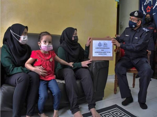 Mazlan menyampaikan sumbangan kepada anak yatim (dari kiri) Auni Firdina Batrisya Zakri, 13, Azka Adreena, 4, dan Ayra Irdina Batrisya, 11, pada Program Lawatan Kebajikan ke Rumah Anak Yatim Warga PDRM di Perumahan Pasukan Simpanan Persekutuan pada Ahad. - Foto Bernama