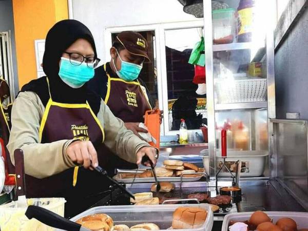 Noor Azlina Jaafar (kiri) dan Basir menyediakan makanan yang dipesan pelanggan di rumah mereka.