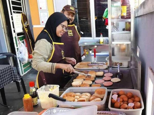 Noor Azlina Jaafar (kiri) dan Basir menyediakan makanan yang dipesan pelanggan di rumah mereka.