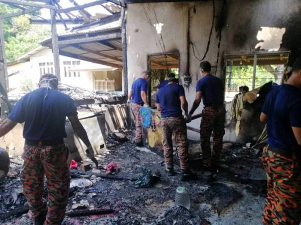 Anggota bomba dari BBP Kuala Terengganu membersihkan sisa-sisa kebakaran kediaman warga emas, Semek Mamat, 62 di Kg Kesom, Manir, Kuala Terengganu.