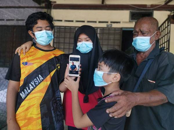Said (kanan) dan tiga cucunya menunjukkan gambar Shahrul Nizwan