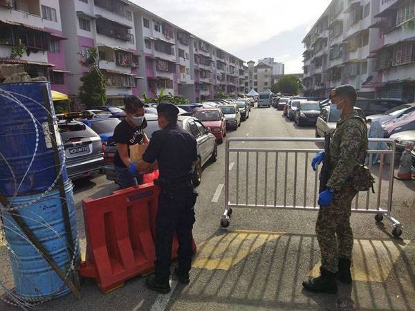 Penduduk mengambil barangan daripada anggota polis di PKPD Pangsapuri Merpati (A) di sini pada Isnin.