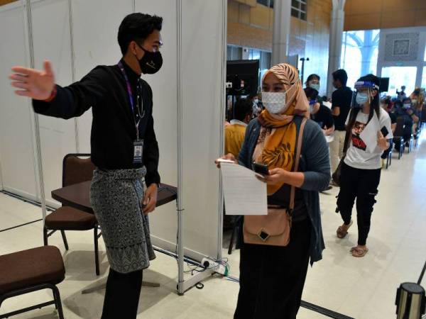 Petugas Pusat Pemberian Vaksin (PPV) Mega Movenpick Hotel dan Pusat Konvensyen mengenakan pakaian baju melayu dan baju kurung sempena sambutan Aidiladha pada Selasa. - Foto Bernama