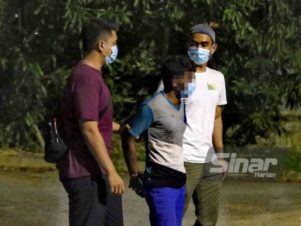 Suspek (tengah) ditahan polis di lokasi kejadian.