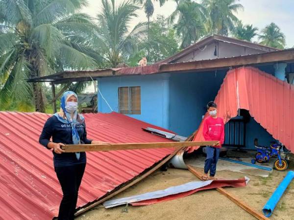 Siti Mariam dan anaknya menunjukkan keadaan di hadapan rumah mereka yang rosak teruk selepas kejadian ribut yang melanda pada Rabu.