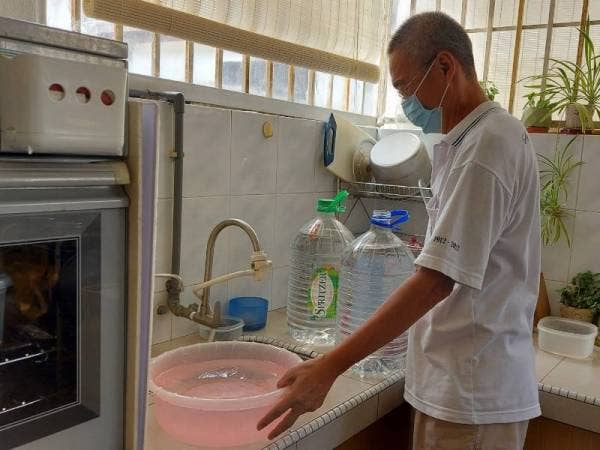 Thomas menunjukkan bekalan air yang disimpan selepas kawasan perumahannya kerap mengalami gangguan bekalan air.