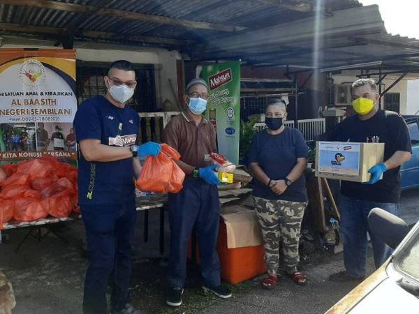 Mohd Jazri (kiri) dan Khairul Nizam (kanan) menyampaikan sumbangan kepada penerima bantuan pada Isnin.